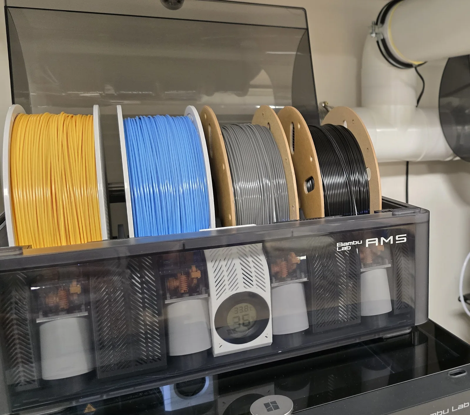 Spools of yellow, blue, gray and black 3D printing filament
